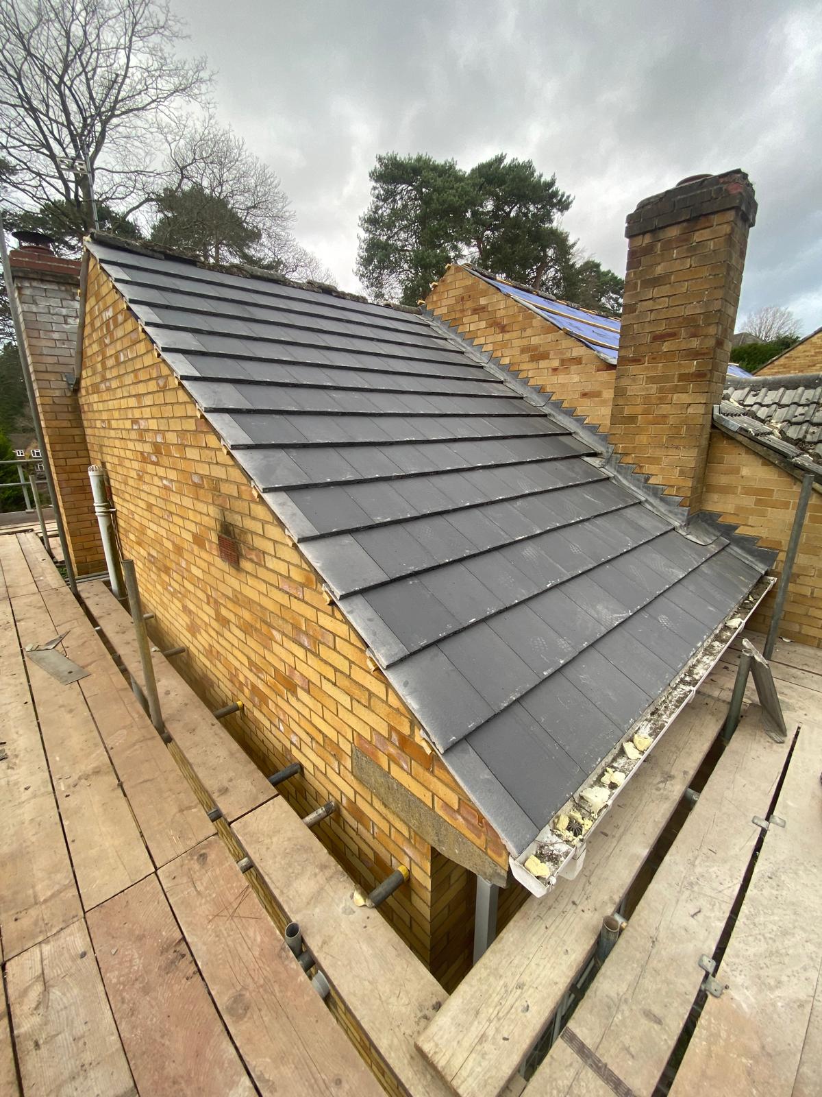 DM Roofing — natural slates stacked on battens ready to be laid, showing the scale of the full re-roof project