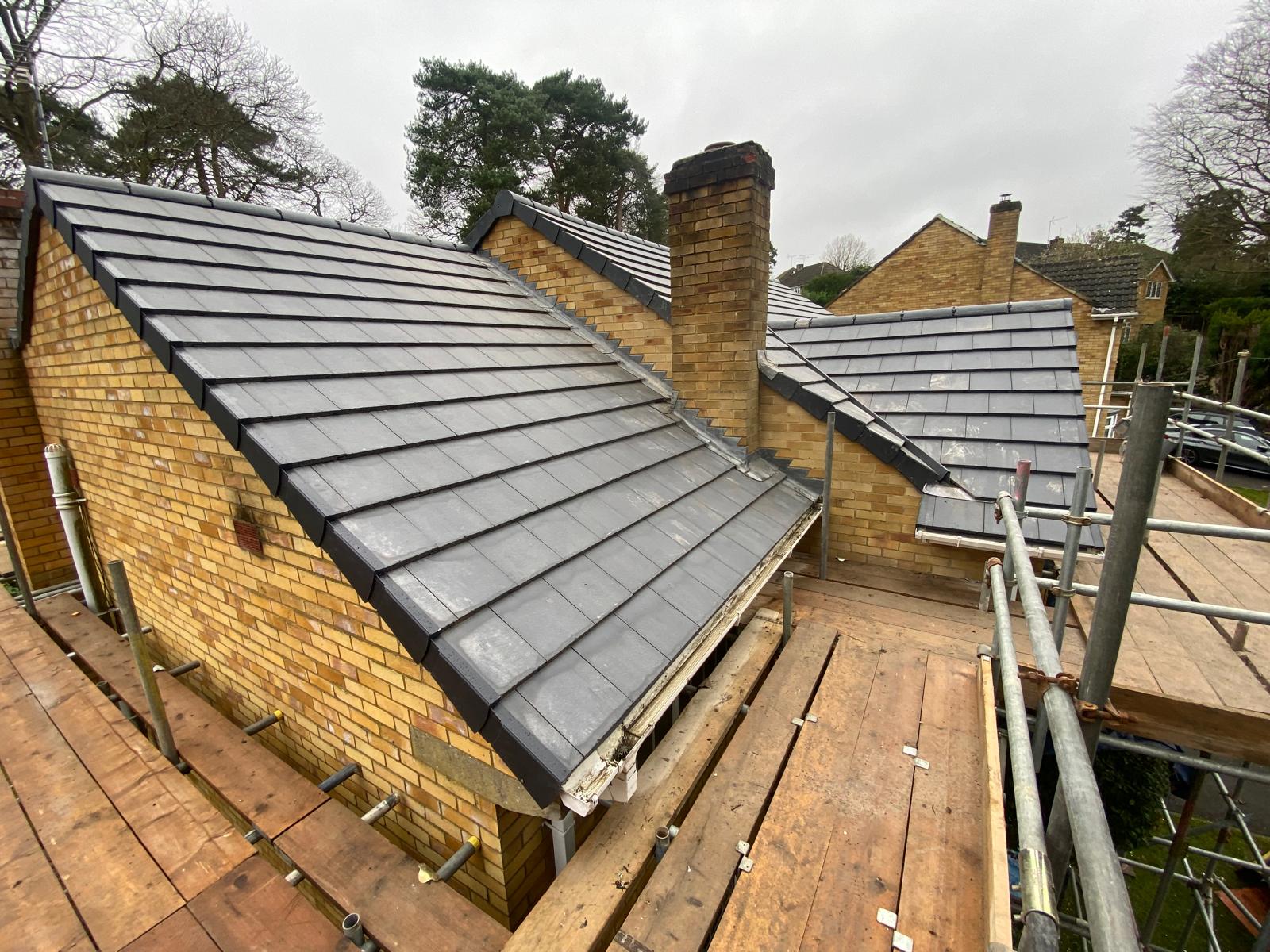 DM Roofing — completed Russell Grampian re-roof showing multiple roof sections, clean ridge lines and chimney lead flashing, residential property