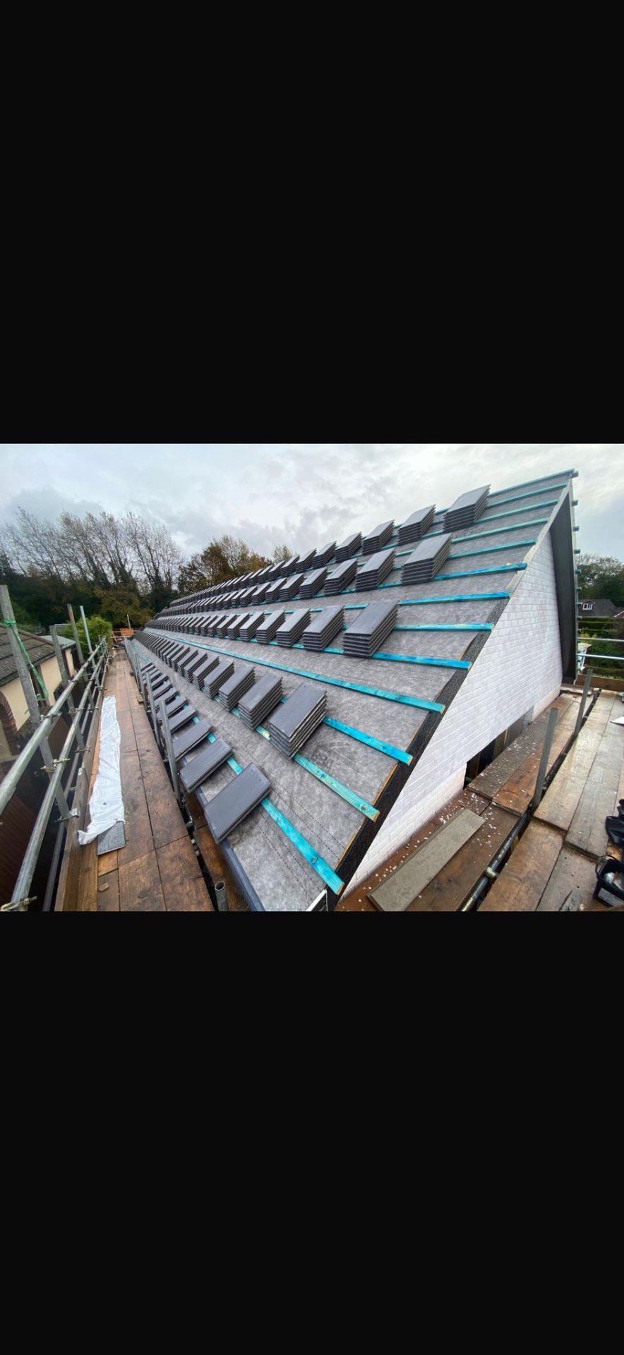 DM Roofing — natural slate roof mid-installation, slates being laid on timber battens over breathable membrane